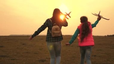 gençler pilot ve astronot olmak istiyorum. Mutlu kızlar gün batımında sahada oyuncak uçakla koşarlar. mutlu bir çocukluk kavramı. çocuk oyuncak uçak oynarken. Kızlar uçmayı ve pilot olmayı hayal.