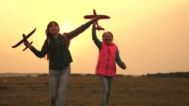 gençler pilot ve astronot olmak istiyorum. Mutlu kızlar gün batımında sahada oyuncak uçakla koşarlar. mutlu bir çocukluk kavramı. çocuk oyuncak uçak oynarken. Kızlar uçmayı ve pilot olmayı hayal.