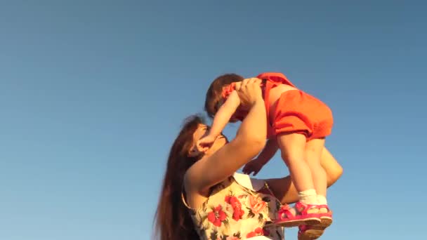 Mutter wirft ihre Tochter in den Himmel. Mutter spielt mit kleinem Kind vor blauem Himmel. glückliche Familie spielt am Abend gegen den Himmel. Mutter wirft das Baby hoch, Baby lächelt. Zeitlupenfilme. — Stockvideo