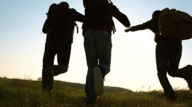 neşeli gezginler güneşe tek er teker koşarlar. iş adamlarının takım çalışması. Sırt çantaları ile mutlu turistler koşmak ve ellerini sallamak. iş ekibi kazanmak ve başarılı olmak için acele ediyor. Yavaş çekim.