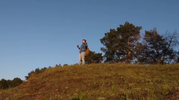 Viajero chica, se para en la cima de la colina bebiendo café en un vaso. turista bebiendo té caliente y viendo el atardecer. Descanso aventurero después de alcanzar la meta. concepto de libertad y sueños . — Vídeos de Stock