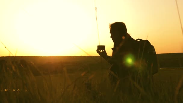 Bevande turistiche tè caldo e guarda il tramonto. riposo dopo aver raggiunto l'obiettivo. Viaggiatore solitario seduto sulla cima di una collina a bere caffè in thermos. concetto di libertà e sogni. mondo senza frontiere — Video Stock