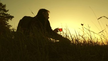 turistik içecekler sıcak çay ve gün batımı nı izler. bir tepenin tepesinde oturup termos kahve içen yalnız gezgin. hedefe ulaştıktan sonra dinlenmek. özgürlük ve hayaller kavramı. sınırları olmayan dünya