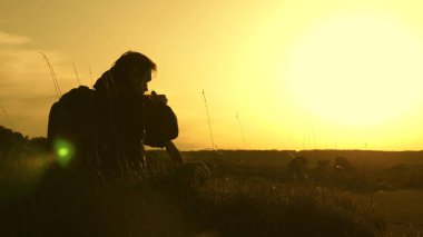 bir tepenin tepesinde oturup termos kahve içen yalnız gezgin. turistik içecekler sıcak çay ve gün batımı nı izler. hedefe ulaştıktan sonra dinlenmek. özgürlük ve hayaller kavramı. sınırları olmayan dünya