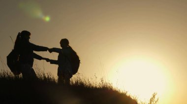 tatil seyahat ve dağda dans anne ve kızı. Dağın tepesinde, gün batımına bakarak yükseltilmiş elleri olan bir kadın. Hiker kız yetiştirmek onu el yukarı, kutluyor zafer ve zevk sahne.