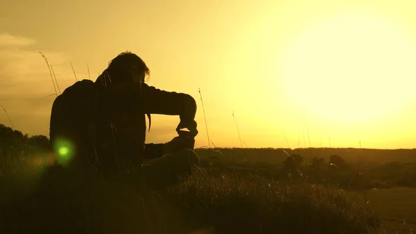 Viajero solitario sentado en la cima de una colina bebiendo café en termos. turista bebe té caliente y observa atardecer. descansar después de alcanzar la meta. concepto de libertad y sueños. mundo sin fronteras —  Fotos de Stock