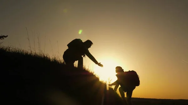 gezgin adam bir tepenin tepesine tırmanan bir kız elini uzatır. gezginler el tutarak uçuruma tırmanıyorlar. iş adamlarının takım çalışması. Mutlu bir aile tatilde. turistler dağın tepesinde sarılmak