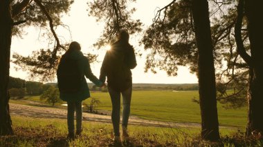 team work Hiker Girls Raising Her Hands Up, Celebrating Victory And Enjoying Scenery. teamwork mother and daughter on vacation travel through forest with backpack, raise their hands to top.