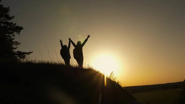 Famiglia mamma e figlia vacanze di viaggio. Donna con le mani alzate sulla cima di una montagna guardando il tramonto. Ragazza escursionista alzando la mano, celebrando la vittoria e godendo di bei paesaggi e natura . — Foto Stock