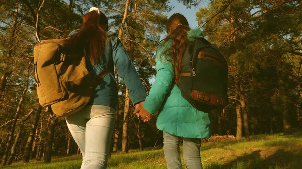 mother and daughter travelers walking through the woods with a backpack. Hiker Girs in a pine forest. The tourist enjoys life and nature. vacation adventure travel. Happy family travels.