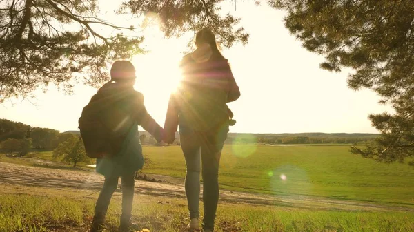 Teamwork Wandermädchen heben die Hände, feiern den Sieg und genießen die Landschaft. Teamwork Mutter und Tochter im Urlaub reisen mit Rucksack durch den Wald, heben die Hände nach oben. — Stockfoto