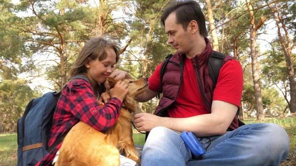 Happy family with a dog and children in a camping trip. Carefree teenagers with their father on a day off. Hiking. Vacation. A dog breeder with a dog and children for a walk.