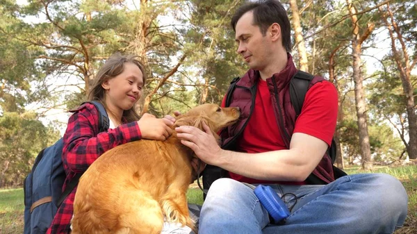 Happy family with a dog and children in a camping trip. Carefree teenagers with their father on a day off. Hiking. Vacation. A dog breeder with a dog and children for a walk.