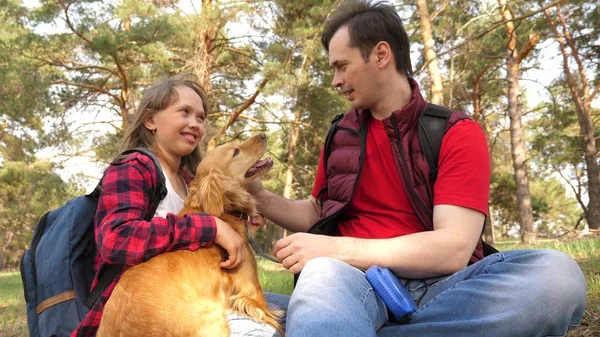 Happy family with a dog and children in a camping trip. Carefree teenagers with their father on a day off. Hiking. Vacation. A dog breeder with a dog and children for a walk.