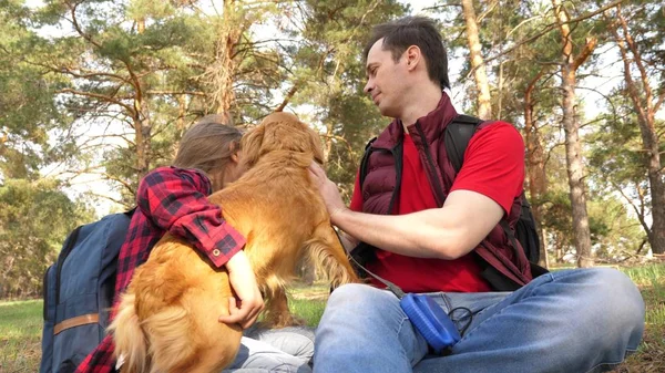 Happy family with a dog and children in a camping trip. Carefree teenagers with their father on a day off. Hiking. Vacation. A dog breeder with a dog and children for a walk.