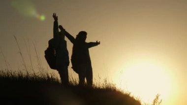 Hiker Girl Up Elini Yükselterek, Zafer Kutluyor ve Sahne Zevk. anne ve kızı tatilde seyahat ve dağda dans. Gün batımına bakan dağın tepesinde elleri havada olan kadın.