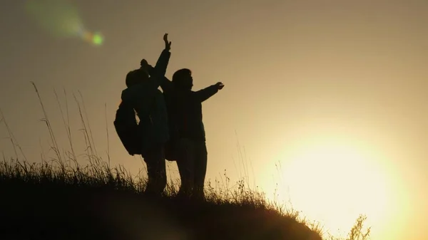 Ragazza escursionista alzando la mano, celebrando la vittoria e godendo scenario. mamma e figlia in vacanza viaggiando e ballando in montagna. Donna con le mani alzate sulla cima della montagna guardando il tramonto . — Foto Stock