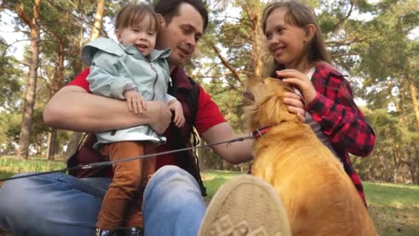 Papa Züchter mit Kindern und Hund spazieren. eine glückliche Familie. Papins-Tag. Vater und Töchter. Pflege und Zucht von Hunden. Haustiere. Teamwork. Den Hund tätscheln. — Stockvideo