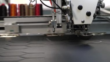 Robotik terzilik üretim hattında çalışır. Robot dikiş makinesi. bilgisayar dikiş makinesini kontrol eder. otomatik dikiş makinesi. suni deri üzerinde iğne nakış deseni.