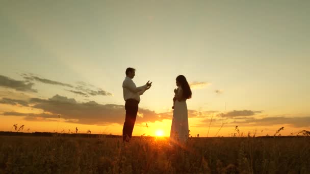 Mamá sostiene a su pequeña hija en sus brazos y se la da a su padre. La hija juega con mamá y papá al sol. Concepto de familia feliz e infancia. .. Trabajo en equipo . — Vídeo de stock