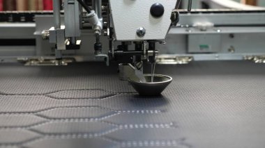 Robot dikiş makinesi. otomatik dikiş makinesi. Robotik terzilik üretim hattında çalışır. Bilgisayar dikiş makinesini kontrol eder. suni deri üzerinde iğne nakış deseni.