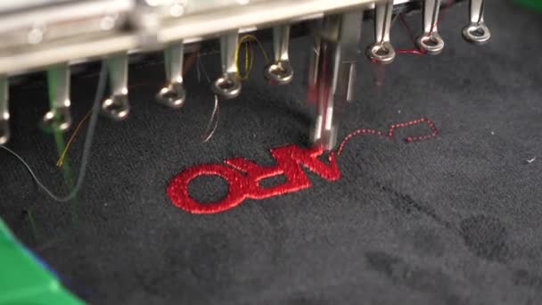 Robot naaimachine. Automatische naaimachine. een geautomatiseerd machine Borduur patroon met rode draden op een zwarte doek. Robotica werkt in het afstemmen van de productielijn. — Stockvideo