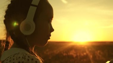 kız çocuk güneşte müzik hayalleri. genç kız müzik dinlerken ve gün batımını izliyor. Parkta güzel bir gündoğumu ışınları kulaklıkla dans Mutlu kız.