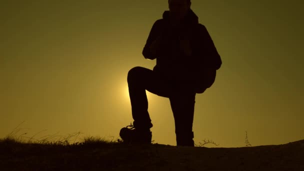 Os viajantes escalam a colina nos raios do sol um por um. Movimento lento. trabalho de equipa de pessoas de negócios. turistas viajam com mochilas. A equipe de negócios está com pressa de ganhar e ter sucesso . — Vídeo de Stock