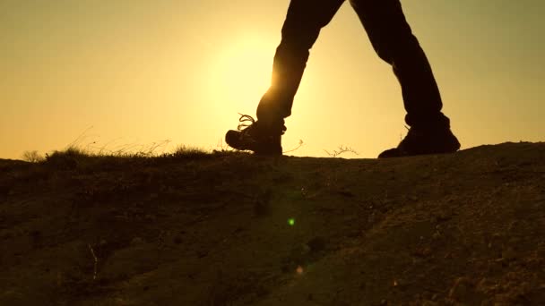 Los turistas caminan en la montaña en rayos de una hermosa puesta de sol. pies de viajeros suben la colina en los rayos del sol amarillo. trabajo en equipo de gente de negocios. equipo de negocios tiene prisa por ganar y tener éxito . — Vídeo de stock