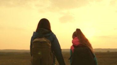 Kızlar yürüyüşte. Kadınlar gün batımında sırt çantasıyla seyahat emzler. Turistler anne ve çocuk gün batımına gidin. Spor turizmi kavramı. Takım sporları ailesi. turist takım çalışması kızlar