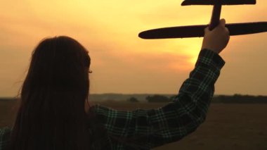 çocuklar oyuncak uçak oynarlar. Kızlar uçmayı ve pilot olmayı hayal ler. Yavaş çekim. Mutlu kız kardeşler sahada gün batımında bir oyuncak uçak ile çalıştırın. Mutlu bir aile kavramı.