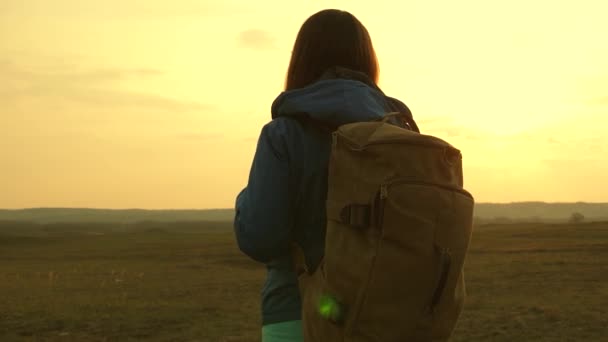Vrijheid en onafhankelijkheid. Hiking. Mooi meisje reiziger met een rugzak gaat te voet bij zonsondergang. Toeristische meisje. Concept in de campagne. — Stockvideo
