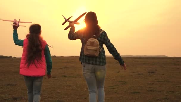 As crianças querem se tornar piloto e astronauta. Meninas felizes correm com avião de brinquedo ao pôr-do-sol no campo. conceito de uma infância feliz. criança brincando de brinquedo avião. Meninas sonham em voar e se tornar um piloto . — Vídeo de Stock