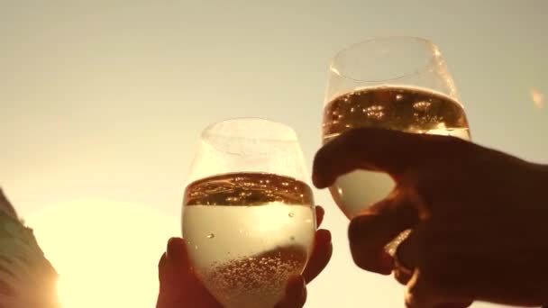 Champagne gnistrar och skum i solen. par i kärlek hålla vinglas med mousserande vin på bakgrund av solnedgången. närbild. lagarbete av älskande par. firar framgång och seger. Slow motion — Stockvideo
