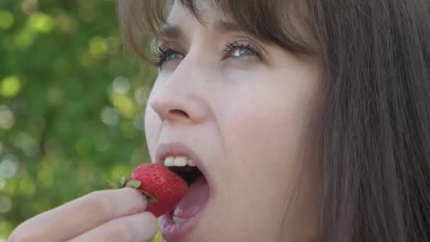 Mooi meisje dat zure aardbei rimpel en het glimlachen eet. Close-up. Vitamine en Berry dieet voor vrouwen. gelukkig meisje eten van aardbeien in de zomer in de tuin. Heerlijke aardbei dessert. — Stockvideo
