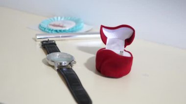 Damat gelini altın yüzük ile bir teklif yapmak için gidiyor. Adam masa saatinden tatil için alır. Yakın çekim