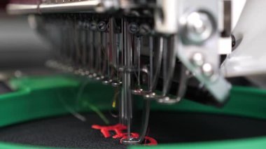 Robot dikiş makinesi. otomatik dikiş makinesi. siyah bir bez üzerinde kırmızı iplik ile otomatik makine nakış deseni. Robotik üretim hattı terzilik çalışır.