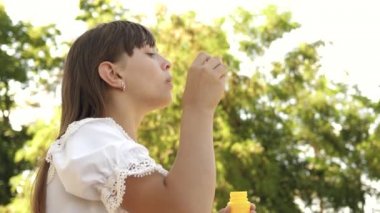 İlkbahar, yaz ve gülümseyen içinde parkta sabun köpüğü üfleme güzel kız. Ağır çekim. parkta oynayan genç kız.