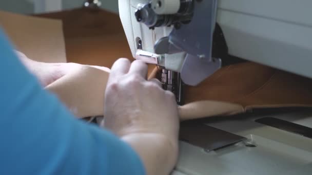 Sarto cuce pelle marrone in un laboratorio di cucito. processo di cucire in pelle artificiale. ago della macchina da cucire in movimento. due aghi della macchina da cucire si muove rapidamente su e giù, primo piano . — Video Stock