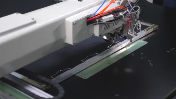 La robótica trabaja en la línea de producción de sastrería. El ordenador controla la máquina de coser. patrón de bordado de aguja en cuero artificial. Robot máquina de coser. máquina de coser automática . — Vídeo de stock