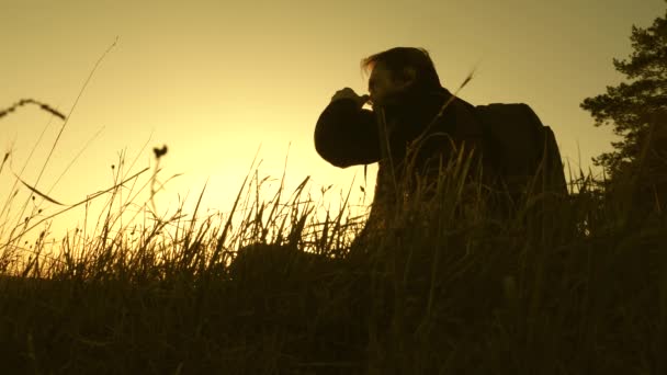 Viajero solitario sentado en la cima de una colina bebiendo café en termos. turista bebe té caliente y observa atardecer. descansar después de alcanzar la meta. concepto de libertad y sueños. mundo sin fronteras — Vídeos de Stock