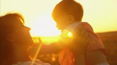 Günbatımı ve gülüyor annesi bebek saçlarından sürükler.