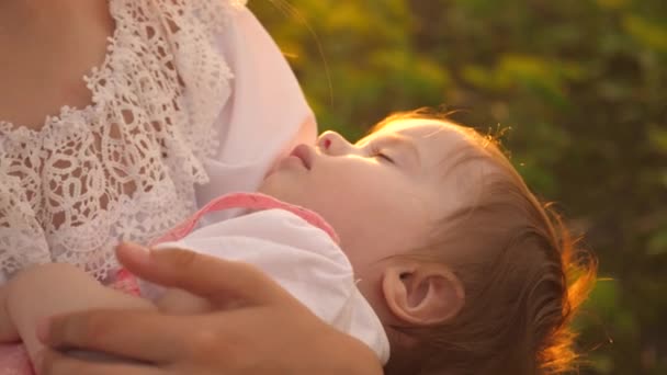 Um bebezinho dorme nos braços da mãe, ao pôr-do-sol, a fotografar em câmara lenta — Vídeo de Stock