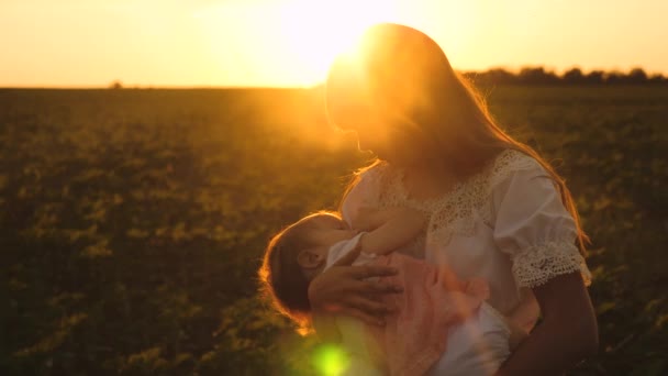 Мама гуляет с маленьким ребенком в летнем парке на закате, ребенок засыпает на руках матерей, замедленная съемка — стоковое видео