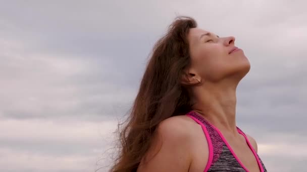 La mujer camina con el tiempo nublado por la noche. Primer plano. Hermosa chica con el pelo largo desaliñado por el viento se regocija en la lluvia y sonríe . — Vídeo de stock