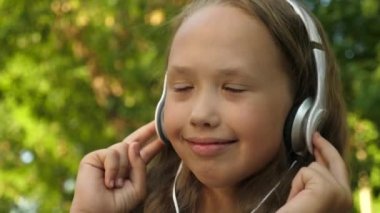 komik bebek müzik dinliyor. kulaklıkmutlu kız müzik dinlerken ve yaz Park'ta dans. yakın çekim.