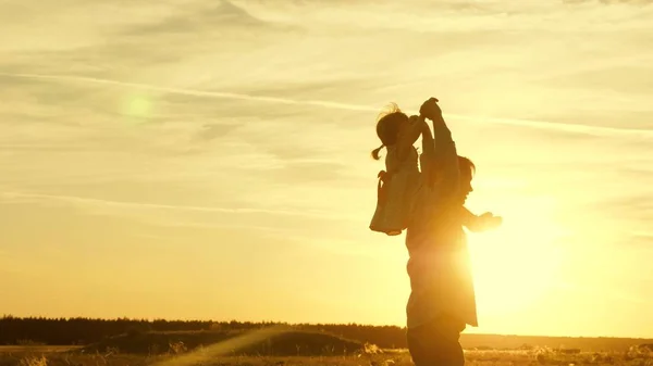 Papa dansen op zijn schouders met zijn dochter in de zon. Vader reist met baby op zijn schouders in stralen van zonsondergang. Een kind met ouders loopt bij zonsondergang. gelukkige familie rusten in Park. familieconcept — Stockfoto