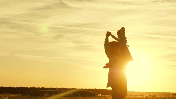 Papà danzava sulle spalle con sua figlia al sole. Papà viaggia con il bambino sulle spalle in raggi di tramonto. Un bambino con i genitori cammina al tramonto. famiglia felice che riposa nel parco. concetto di famiglia — Foto Stock