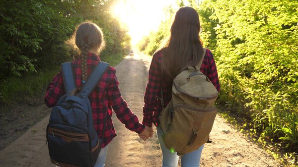 Hiker Girl. girls travel with backpacks on a country road. women tourists go to the sunset. Happy family on vacation travels. sports tourism concept.