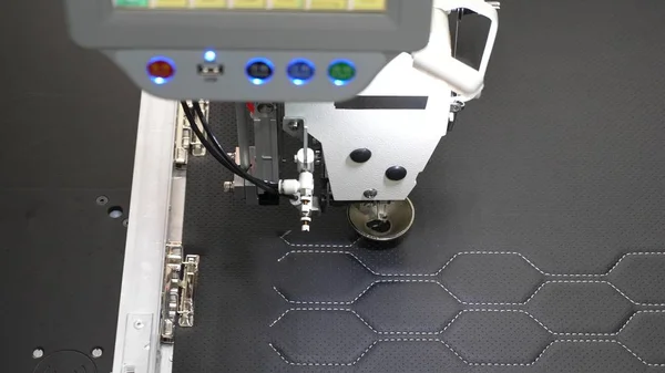 La robótica trabaja en la línea de producción de sastrería. Robot máquina de coser. máquina de coser automática. El ordenador controla la máquina de coser. patrón de bordado de aguja en cuero artificial . — Foto de Stock